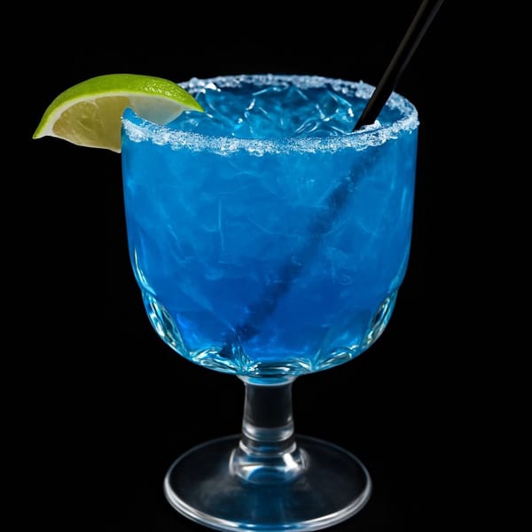 Blue margarita with a salted rim, lime wedge, and black straw against a dark background.