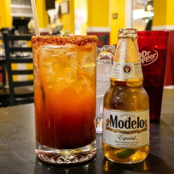 A Modelo Especial beer, a michelada, and a Dr. Pepper on a table in a vibrant restaurant.
